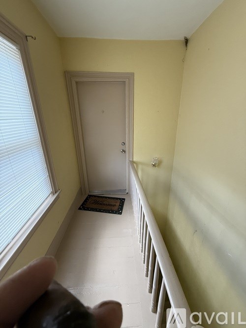 A hallway with a white railing and a white door.