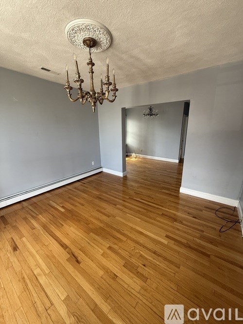 A room with wooden flooring and a chandelier.