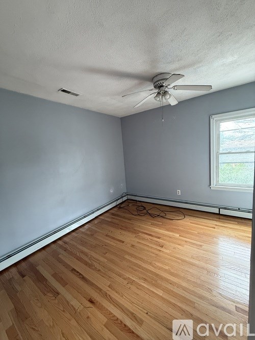 A room with wooden flooring and a ceiling fan.
