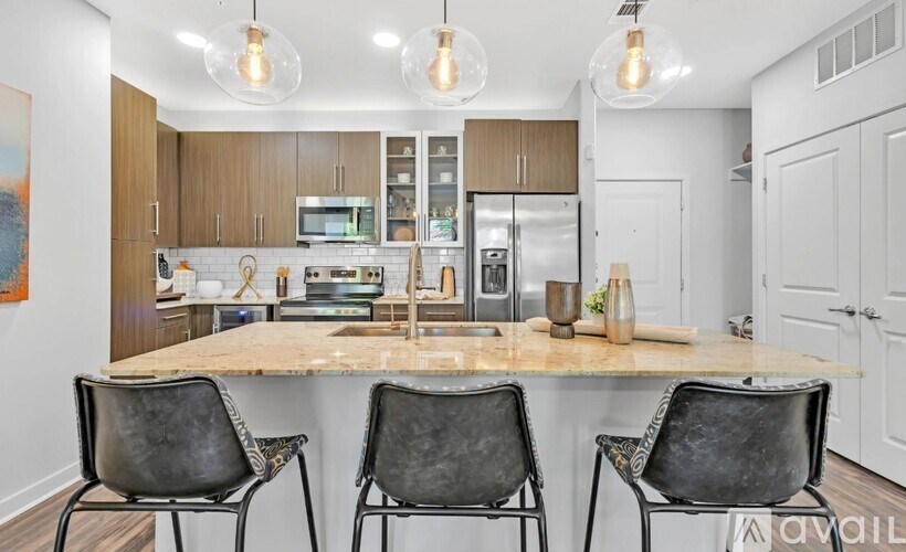 A kitchen with a marble countertop and three black chairs.