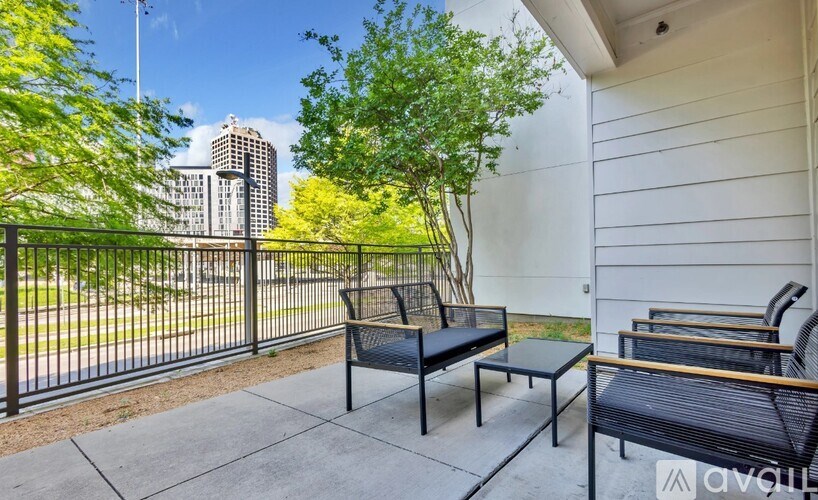 A patio with a black metal table and chairs overlooking a city street.