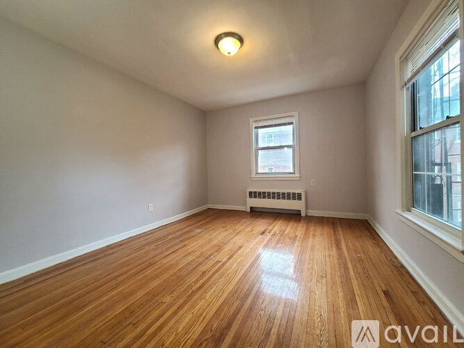 A room with wooden floors and a window with a view of a building outside.