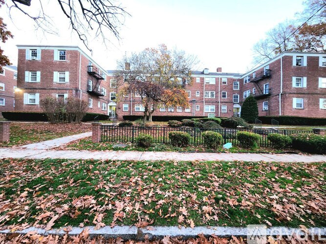 A brick apartment building with a tree in front.