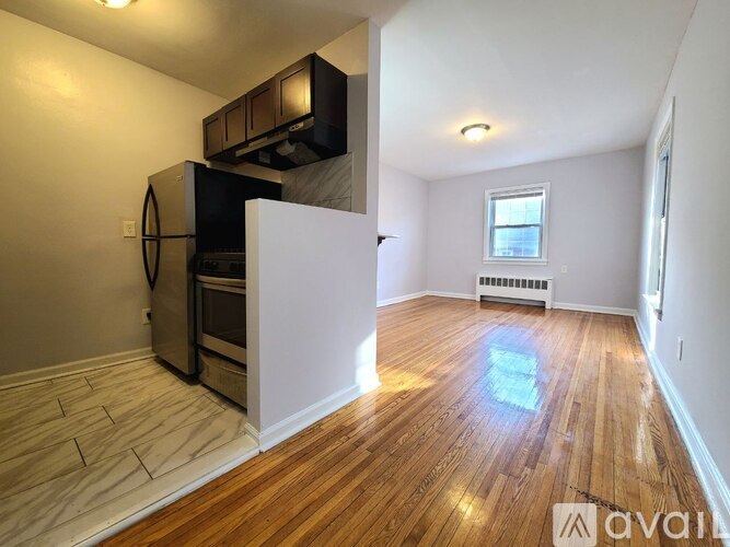 A kitchen area with wood flooring and a white wall.