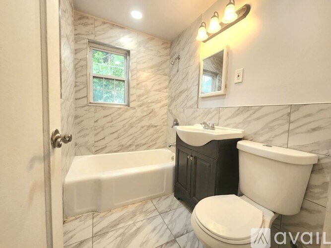 A bathroom with a white tub, sink, and toilet.
