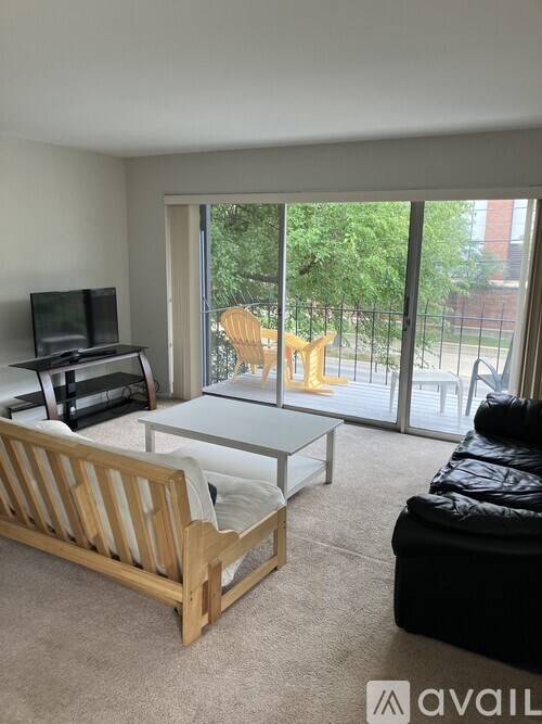 A living room with a television, a sofa, a coffee table, and a sliding glass door leading to a backyard.