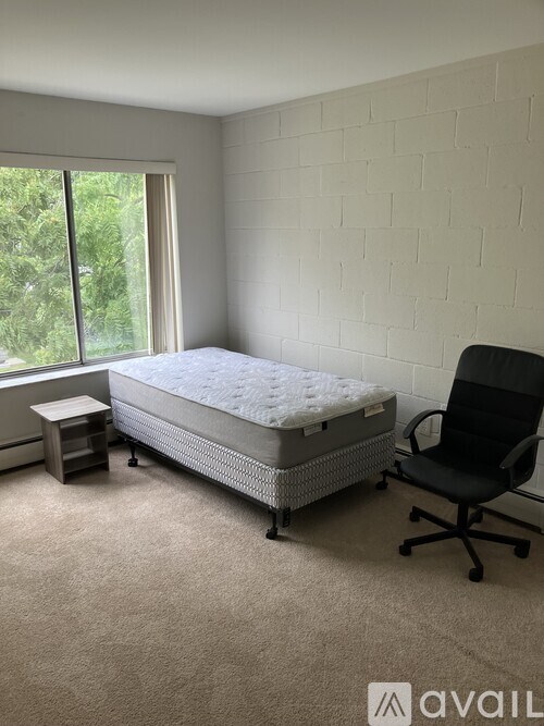 A bedroom with a bed, chair, and carpet.