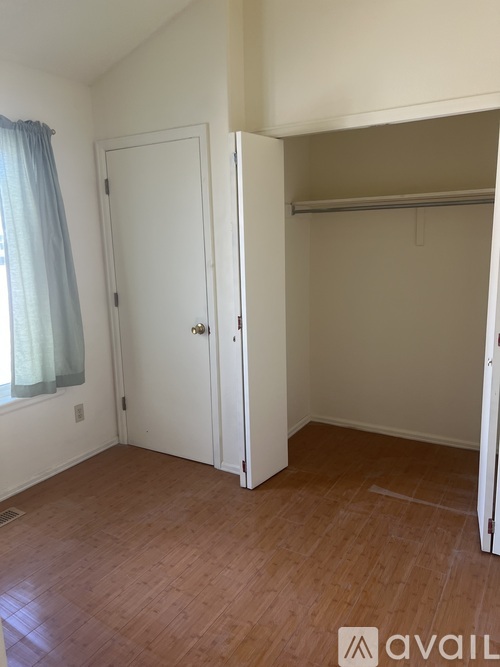 A room with a white door and a window with a blue curtain.