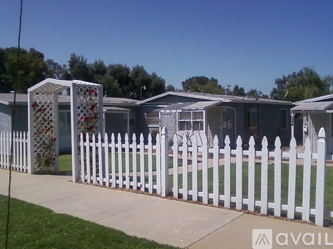 A white picket fence surrounds a row of houses.