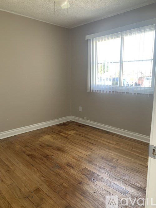 A room with wooden flooring and a window with blinds.