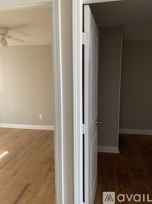 A room with a white door and a fan on the ceiling.