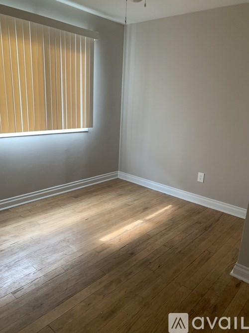 A room with wooden flooring and a window with blinds.