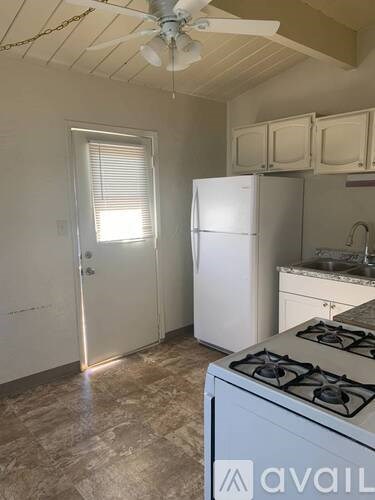 A kitchen with a white fridge, stove, and cabinets.