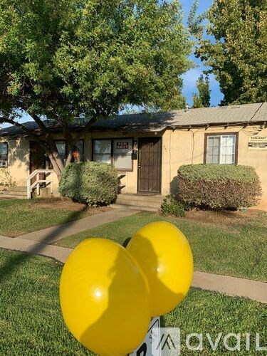 Two yellow balloons in front of a building with a sign that says "available".