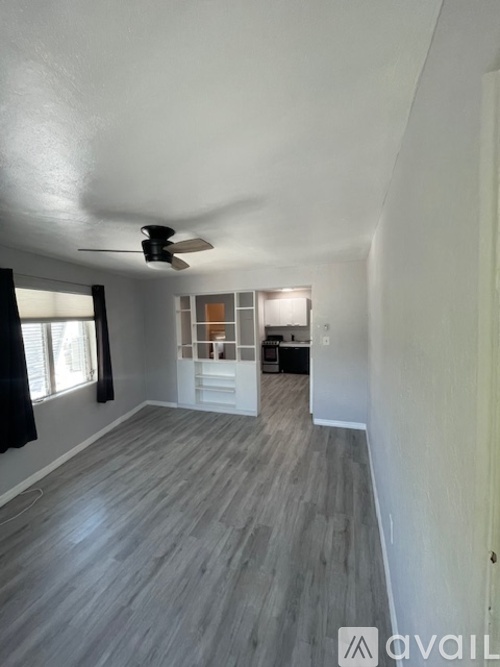 A room with a ceiling fan and wooden flooring.