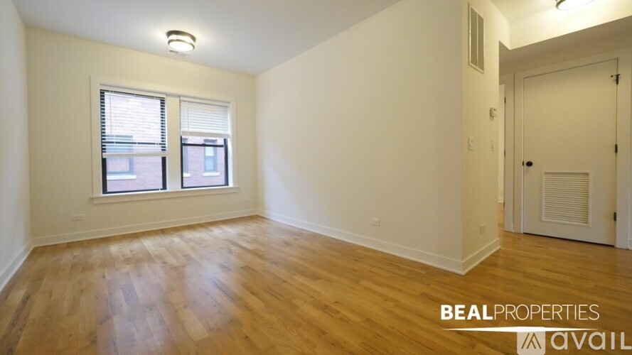 A room with wooden floors and a window with blinds.