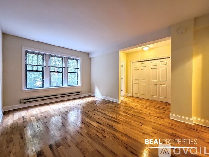 A room with wooden floors and a window with a view of trees.