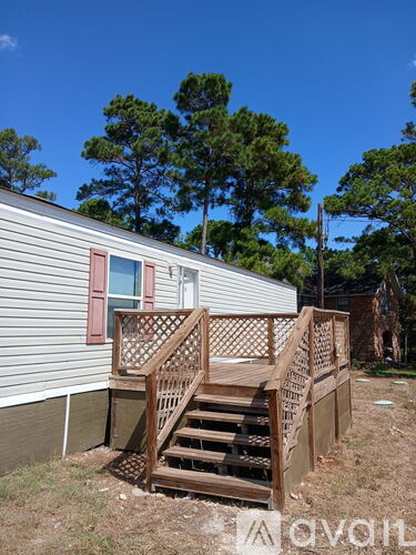 A grey house with a wooden deck and stairs.