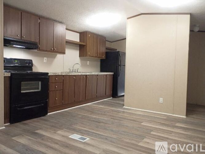 A kitchen with wooden cabinets and a black refrigerator.