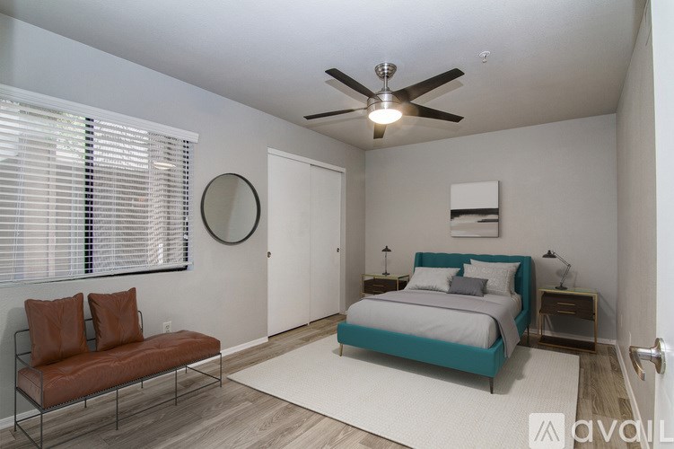 A bedroom with a bed, a bench, and a ceiling fan.
