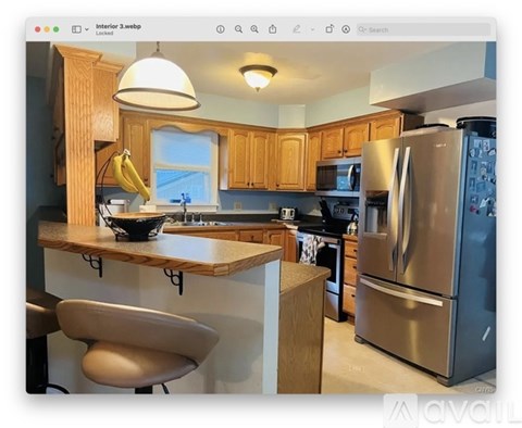 A kitchen with wooden cabinets and a stainless steel refrigerator.
