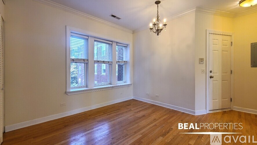 A room with a chandelier, a door, and a window with blinds.