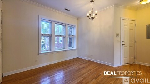 A room with a chandelier, a door, and a window with blinds.