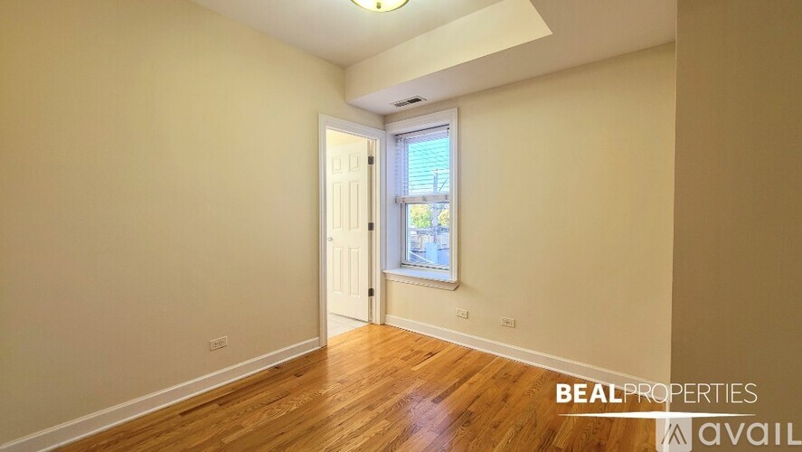 A room with wooden floors and a window with a view of a building outside.