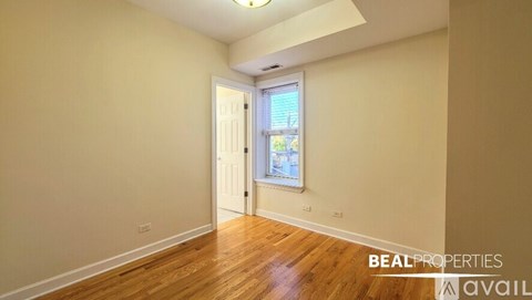 A room with wooden floors and a window with a view of a building outside.