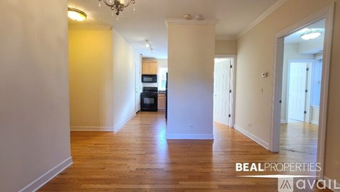 A spacious room with wooden flooring and a chandelier.