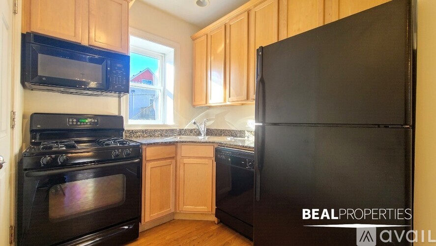 A kitchen with a black refrigerator and black stove.