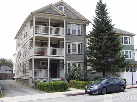 A grey two-story house with a car parked in front.