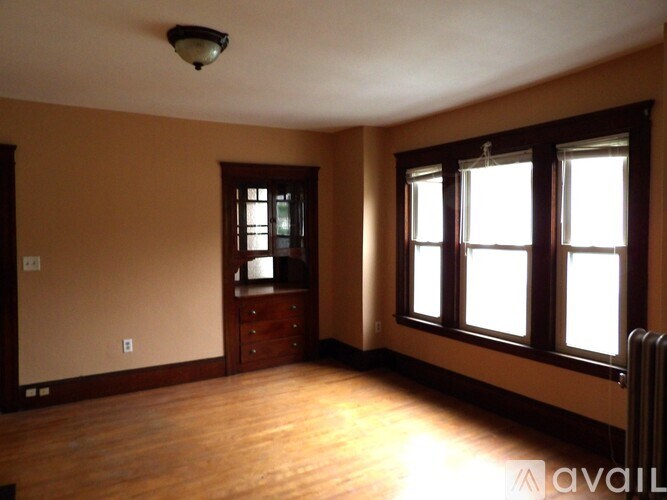 A room with wooden floors and a window with white curtains.