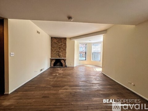 A spacious room with wooden floors and a fireplace.