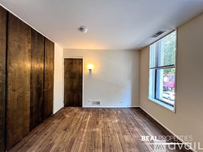 A room with wooden floors and a door leading to another room.