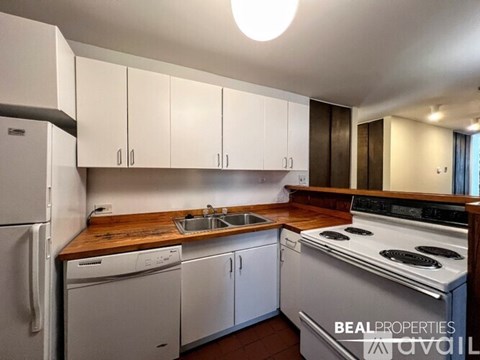 A kitchen with white appliances and wooden countertops.