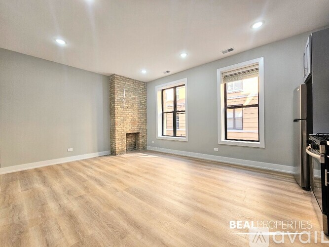 A spacious room with wooden flooring and a brick fireplace.