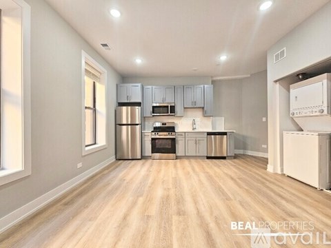 A spacious kitchen with wooden flooring and stainless steel appliances.