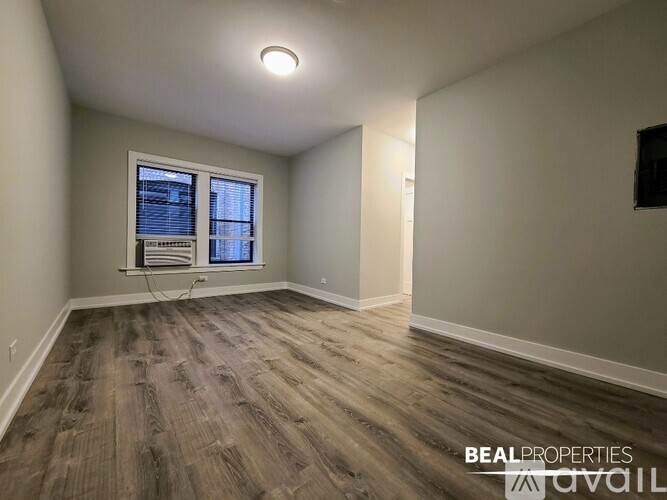 A room with wood flooring and a window with blinds.