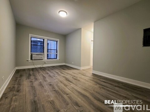 A room with wood flooring and a window with blinds.