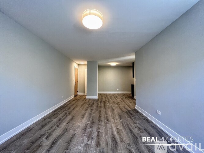 A spacious room with wood flooring and a single light fixture on the ceiling.