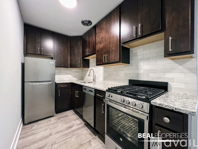 A kitchen with black cabinets and a stainless steel refrigerator.