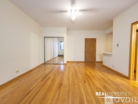 A spacious room with wooden flooring and a sliding glass door.