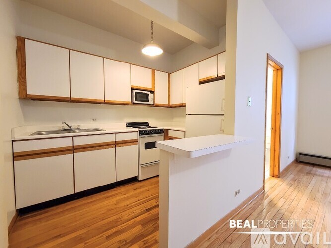 A kitchen with white cabinets and wooden floors.