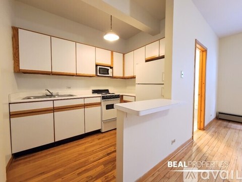 A kitchen with white cabinets and wooden floors.