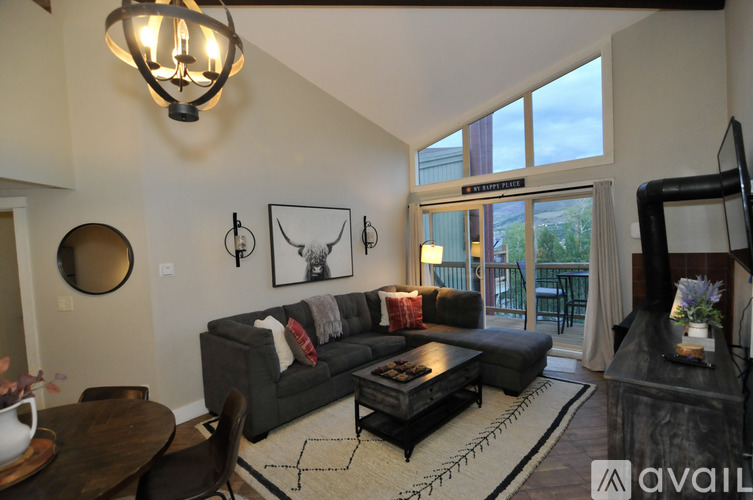 A living room with a grey couch and a chandelier.