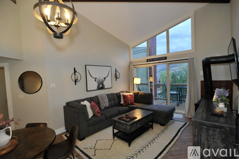 A living room with a grey couch and a chandelier.