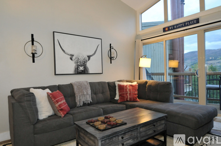 A living room with a grey couch and a picture of a bull on the wall.