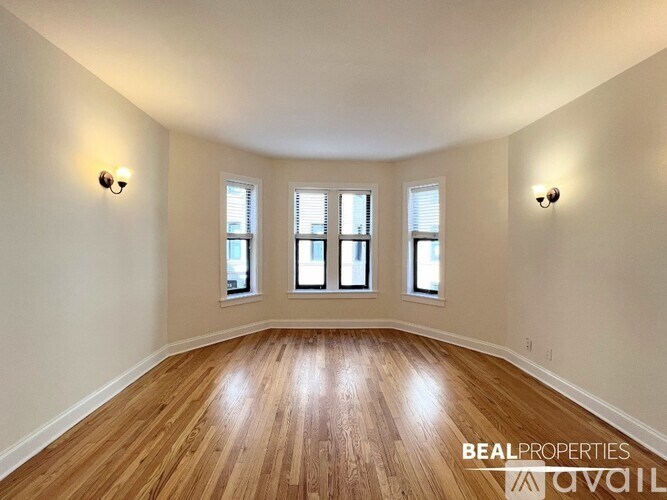 A room with wooden floors and three windows.
