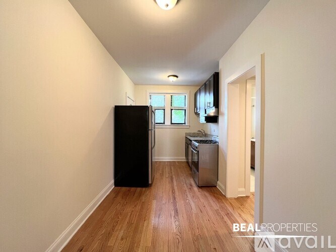 A BEALPROPERTIES sign is on the wall of a room with a black fridge, a stainless steel dishwasher, and a wooden floor.